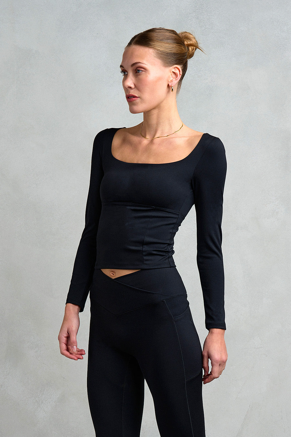 Our model is showcasing the front of the Kensington Square Neck Cross Back top from Stretch Studio London. Featuring long sleeves this top is perfect to elevate your activewear this autumn.